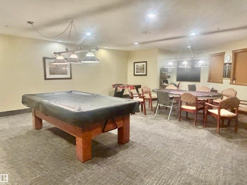 Recreation room featuring a billiards table, card table with seating, and textured carpet flooring - #202 8802 Southfort Dr, Fort Saskatchewan, AB - Indoor Photo Showing Other Room