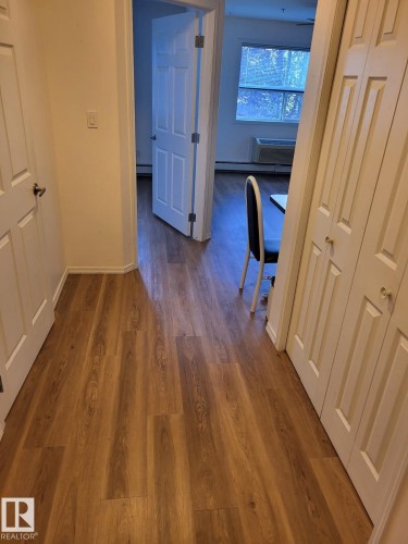 Wood-finish flooring throughout, offering a cohesive aesthetic - #202 8802 Southfort Dr, Fort Saskatchewan, AB - Indoor Photo Showing Other Room