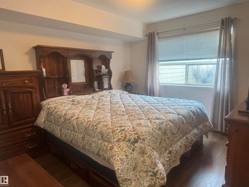 Bedroom featuring wood-finish flooring, a window with horizontal blinds, and neutral-toned walls - #202 8802 Southfort Dr, Fort Saskatchewan, AB - Indoor Photo Showing Bedroom