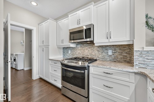 White shaker-style cabinetry with chrome hardware, stainless steel gas range, and built-in microwave - 1323 158 Street Sw, Edmonton, AB - Indoor Photo Showing Kitchen With Upgraded Kitchen