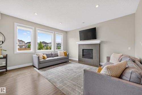 Recessed lighting, wood-finish flooring, and a tiled fireplace with a mantel - 1323 158 Street Sw, Edmonton, AB - Indoor Photo Showing Living Room With Fireplace