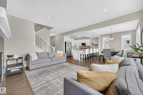 Open-concept living space featuring wood-finish flooring, recessed lighting, white kitchen cabinetry, and an island with bar seating - 1323 158 Street Sw, Edmonton, AB - Indoor Photo Showing Living Room