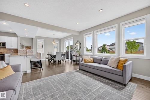 Open-concept living area with dark wood-finish flooring, recessed lighting, and large windows - 1323 158 Street Sw, Edmonton, AB - Indoor Photo Showing Living Room