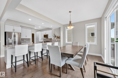 Hardwood flooring, recessed lighting, white cabinetry, stainless steel appliances, and a sliding glass door - 1323 158 Street Sw, Edmonton, AB - Indoor Photo Showing Dining Room