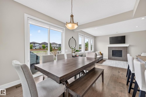 Open-concept living area with wood-finish flooring, recessed lighting, and a modern fireplace with a tiled surround - 1323 158 Street Sw, Edmonton, AB - Indoor Photo Showing Dining Room With Fireplace