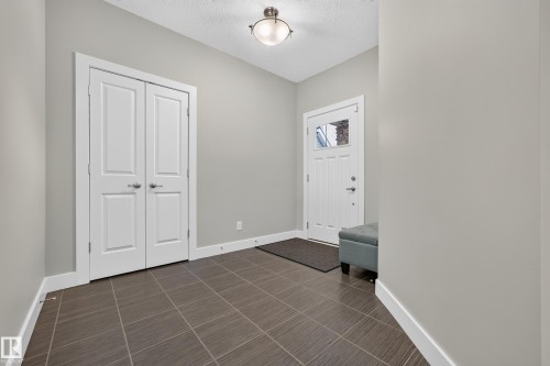 Entryway featuring tile flooring, a white paneled door with glass inserts, and double panel doors - 1323 158 Street Sw, Edmonton, AB - Indoor Photo Showing Other Room