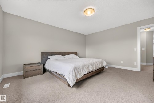 Textured ceiling with a flush-mount light fixture, light gray wall paint, and neutral carpeting - 1323 158 Street Sw, Edmonton, AB - Indoor Photo Showing Bedroom