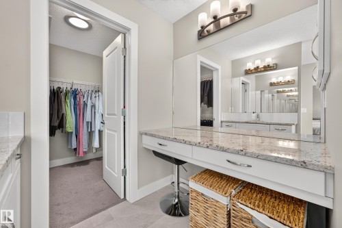 Built-in vanity with a stone countertop, integrated mirror, and overhead light fixture - 1323 158 Street Sw, Edmonton, AB - Indoor