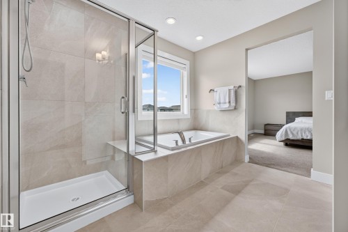 Spacious bathroom with a walk-in shower, built-in soaking tub, large window, and recessed lighting - 1323 158 Street Sw, Edmonton, AB - Indoor Photo Showing Bathroom