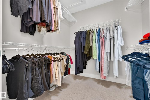 Walk-in closet with carpet flooring, white wire shelving, and multiple hanging rods - 1323 158 Street Sw, Edmonton, AB - Indoor With Storage