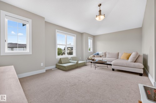Neutral color palette, wall-to-wall carpeting, multiple windows, pendant light fixture, and sloped ceiling - 1323 158 Street Sw, Edmonton, AB - Indoor