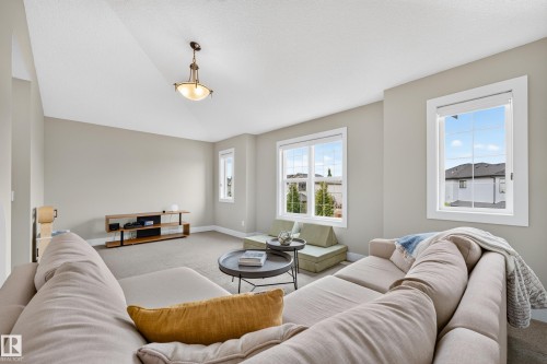 Light-toned wall paint, multiple windows, recessed lighting, and a suspended ceiling light fixture - 1323 158 Street Sw, Edmonton, AB - Indoor Photo Showing Living Room