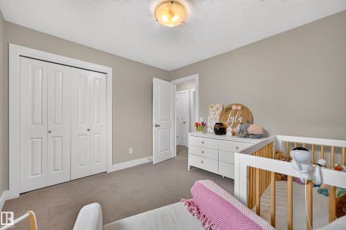 Neutral wall color, wall-to-wall carpeting, overhead lighting, white bi-fold closet doors, and white interior door - 1323 158 Street Sw, Edmonton, AB - Indoor Photo Showing Bedroom