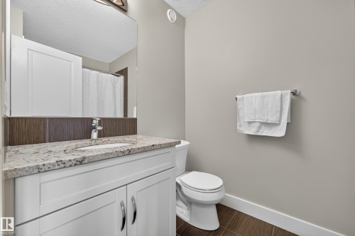 White vanity with under-sink storage, granite countertop with integrated sink, and chrome faucet - 1323 158 Street Sw, Edmonton, AB - Indoor Photo Showing Bathroom