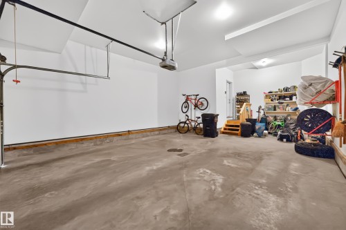 Spacious garage with an automatic door opener, concrete flooring, and built-in wooden shelving for organization - 1323 158 Street Sw, Edmonton, AB - Indoor Photo Showing Garage