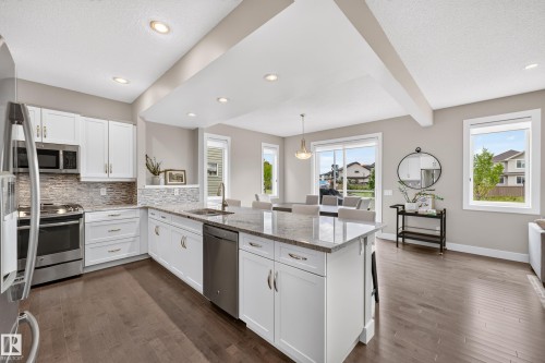 White shaker cabinetry with stainless steel appliances, granite countertops, and mosaic tile backsplash - 1323 158 Street Sw, Edmonton, AB - Indoor Photo Showing Kitchen With Stainless Steel Kitchen With Upgraded Kitchen