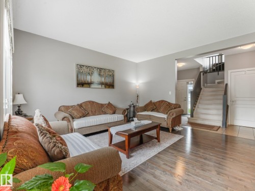 Hardwood flooring, light gray wall color, white trim, and a staircase with dark wood-finish handrails - 1478 37B Avenue Nw, Edmonton, AB - Indoor Photo Showing Living Room