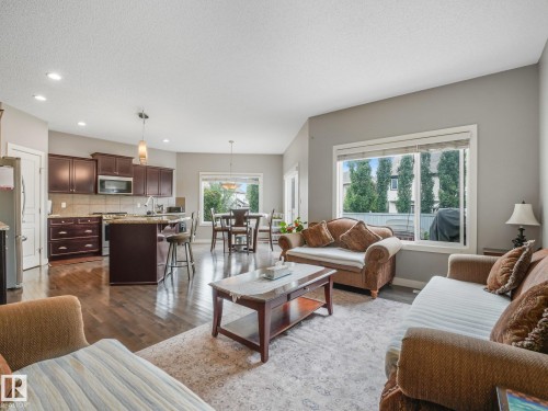 Open-concept living space featuring wood-finish flooring, a kitchen island with seating, dark wood cabinetry, and recessed lighting - 1478 37B Avenue Nw, Edmonton, AB - Indoor Photo Showing Living Room