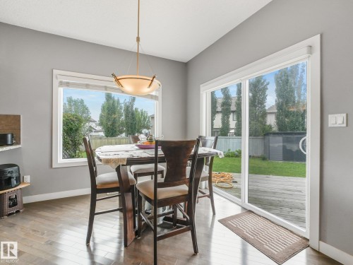 Hardwood-finish flooring, overhead pendant lighting, large picture window, sliding glass door, and a wooden deck - 1478 37B Avenue Nw, Edmonton, AB - Indoor Photo Showing Dining Room