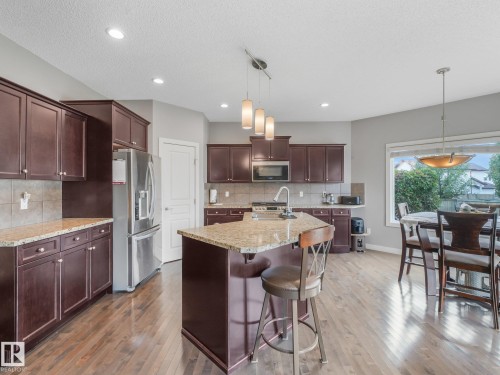 Stainless steel appliances, recessed ceiling lighting, granite countertops, wood-finish flooring, and dark wood cabinetry - 1478 37B Avenue Nw, Edmonton, AB - Indoor Photo Showing Kitchen With Upgraded Kitchen