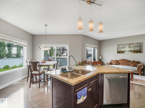 Kitchen island with dual stainless steel sinks, granite-style countertop, and integrated dishwasher - 1478 37B Avenue Nw, Edmonton, AB - Indoor
