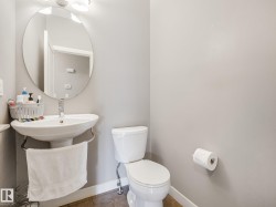 Pedestal sink with chrome faucet, circular wall mirror, and two-bulb vanity light fixture - 