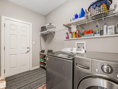 Dedicated laundry space featuring a white paneled door, light-toned walls, and built-in wire shelving - 1478 37B Avenue Nw, Edmonton, AB - Indoor Photo Showing Laundry Room