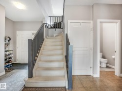 Carpeted staircase with dark wood-finish railings, recessed lighting, and tile flooring in the entry - 
