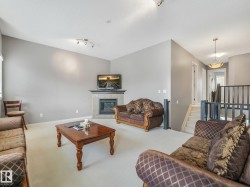 Living area featuring a gas fireplace with a tiled surround, a vaulted ceiling, and recessed lighting - 