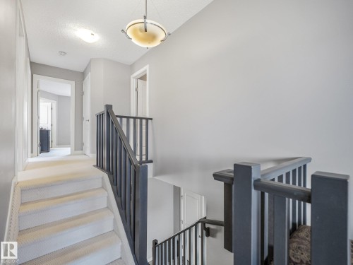 Upper hallway featuring a carpeted staircase, dark wood banister, and a semi-flush mount ceiling fixture - 1478 37B Avenue Nw, Edmonton, AB - Indoor Photo Showing Other Room
