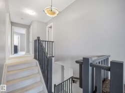 Upper hallway featuring a carpeted staircase, dark wood banister, and a semi-flush mount ceiling fixture - 