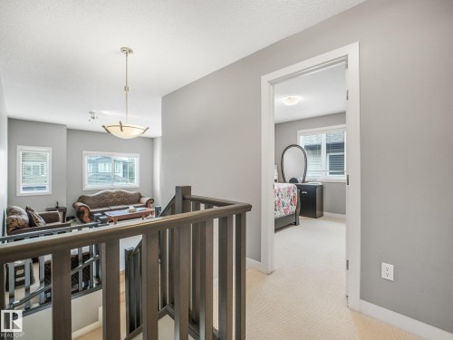Upper-level landing with carpeted flooring and a built-in wood-finish railing - 1478 37B Avenue Nw, Edmonton, AB - Indoor