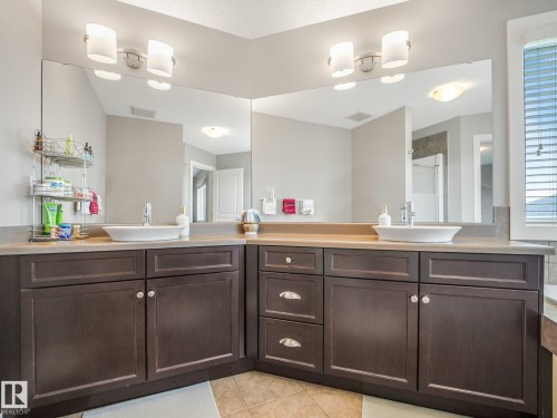 Dual vanity with vessel sinks, dark wood-finish cabinetry, and expansive wall-mounted mirrors - 1478 37B Avenue Nw, Edmonton, AB - Indoor Photo Showing Bathroom