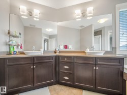 Dual vanity with vessel sinks, dark wood-finish cabinetry, and expansive wall-mounted mirrors - 