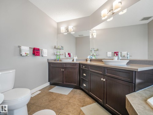Double vanity with vessel sinks, dark wood-finish cabinetry, and expansive mirror - 1478 37B Avenue Nw, Edmonton, AB - Indoor Photo Showing Bathroom