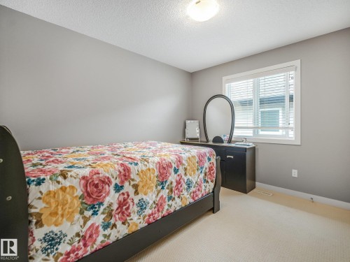 Neutral-toned walls, white trim window with blinds, light-colored carpet flooring, and a flush mount ceiling light - 1478 37B Avenue Nw, Edmonton, AB - Indoor Photo Showing Bedroom