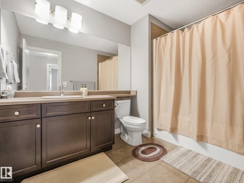 Extended vanity with a single basin, dark wood cabinetry, and a full-width mirror - 1478 37B Avenue Nw, Edmonton, AB - Indoor Photo Showing Bathroom