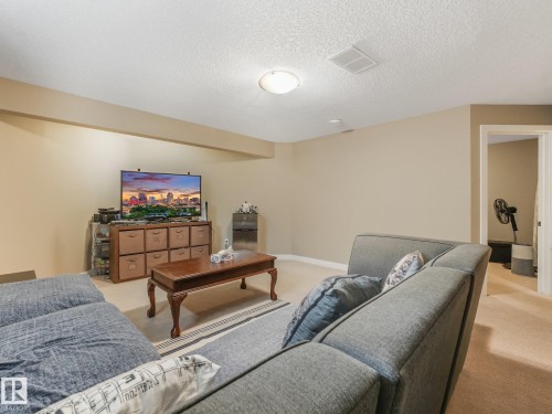 Carpeted living area featuring neutral wall tones, a flush-mount ceiling light, and a framed doorway - 1478 37B Avenue Nw, Edmonton, AB - Indoor