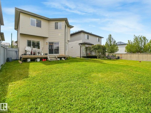 Expansive green space featuring a wooden deck, a second-story window, a sliding glass door, and a privacy fence - 1478 37B Avenue Nw, Edmonton, AB - Outdoor