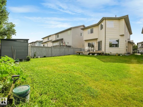 Expansive lawn area with a wood privacy fence, a modern storage shed, and a raised wood deck - 1478 37B Avenue Nw, Edmonton, AB - Outdoor