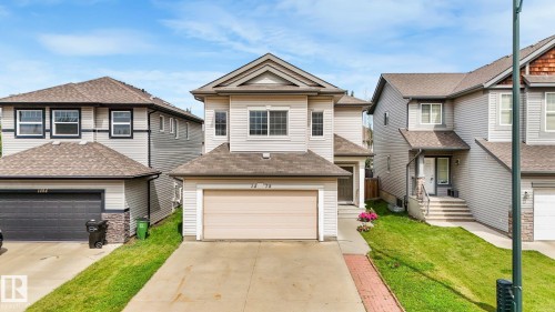 Two-story residence featuring light-toned siding, a front-facing attached garage, and a peaked roofline - 1478 37B Avenue Nw, Edmonton, AB - Outdoor With Facade
