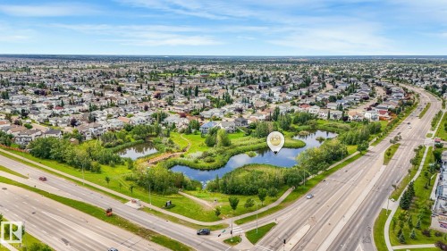 Neighborhood with extensive residential development, surrounding a natural pond feature with established greenery - 1478 37B Avenue Nw, Edmonton, AB - Outdoor With View