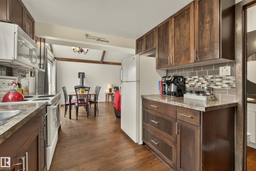 Kitchen featuring wood-finish cabinetry, stone-look countertops, and a subway tile backsplash - 264 Beach Avenue, Rural Barrhead County, AB - Indoor Photo Showing Kitchen