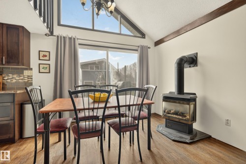 Open-concept dining area featuring wood-finish flooring, a built-in fireplace with a hearth, and a vaulted ceiling with exposed beams - 264 Beach Avenue, Rural Barrhead County, AB - Indoor Photo Showing Dining Room