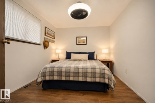 Wood-finish flooring, white horizontal blinds, and a ceiling-mounted light fixture with integrated fan - 264 Beach Avenue, Rural Barrhead County, AB - Indoor Photo Showing Bedroom