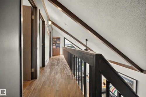 Wood-finish flooring, exposed ceiling beams, and a built-in bookshelf - 264 Beach Avenue, Rural Barrhead County, AB - Indoor Photo Showing Other Room