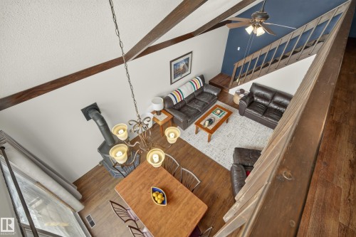 Vaulted ceiling with exposed wood beams, wood-finish flooring, and a wood-burning stove - 264 Beach Avenue, Rural Barrhead County, AB - Indoor Photo Showing Other Room