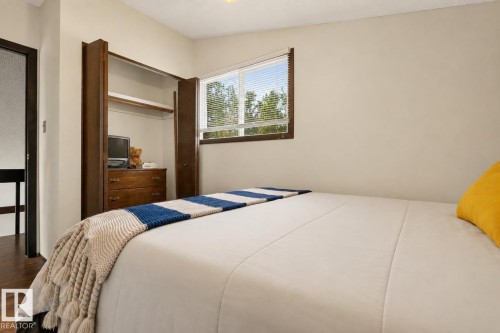 Built-in open shelving with integrated dresser, dark wood-finish window frame, white horizontal blinds, and light-toned wall paint - 264 Beach Avenue, Rural Barrhead County, AB - Indoor Photo Showing Bedroom