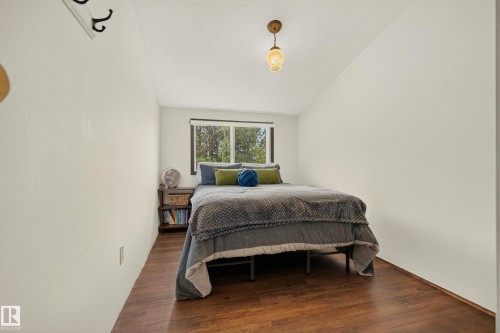 Wood-finish flooring with a window offering natural light, a ceiling-mounted light fixture, and white wall finishes - 264 Beach Avenue, Rural Barrhead County, AB - Indoor Photo Showing Bedroom