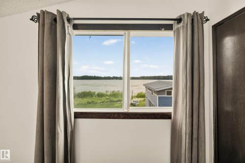 Window with water scenery, white window frame, and a dark wood-finish sill - 264 Beach Avenue, Rural Barrhead County, AB - Indoor
